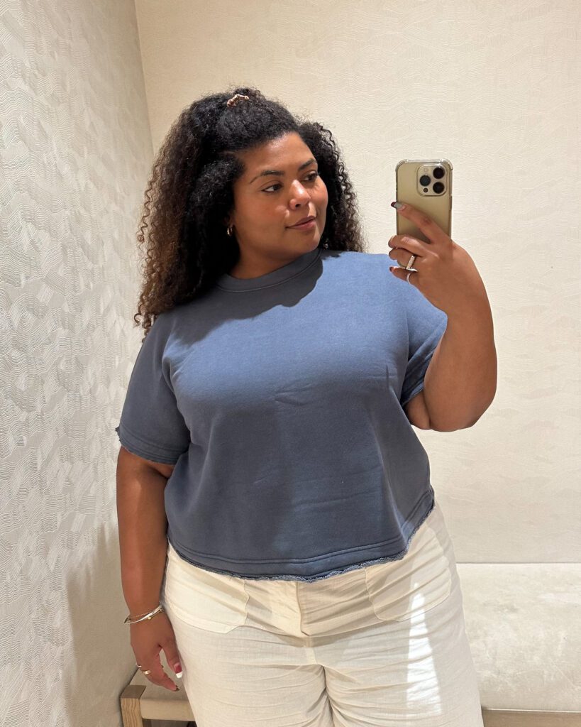 Plus-size woman wearing Banana Republic's Larkspur Cotton-Silk Sweater Tee in dark denim blue with cream pants.